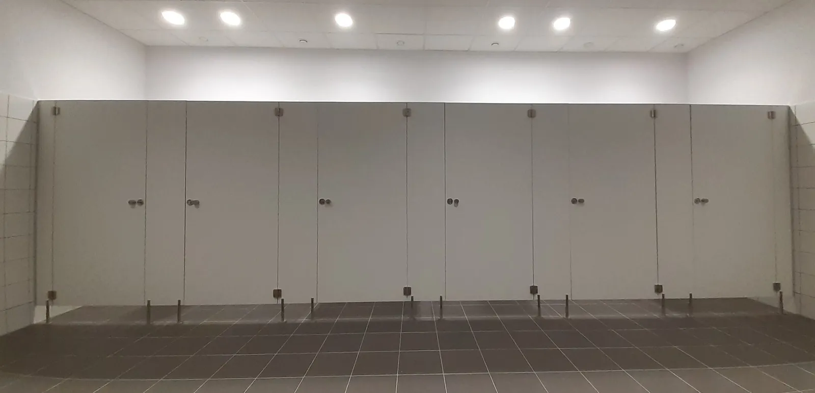 Szare kabiny sanitarne WC z płyty HPL w toalecie publicznej